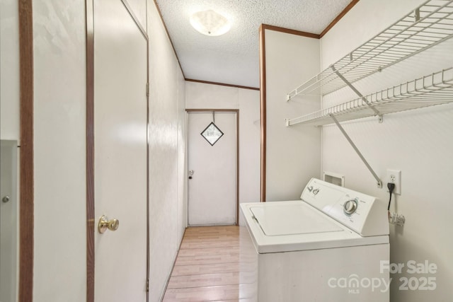 laundry area featuring ornamental molding, laundry area, a textured ceiling, light wood finished floors, and washer / dryer