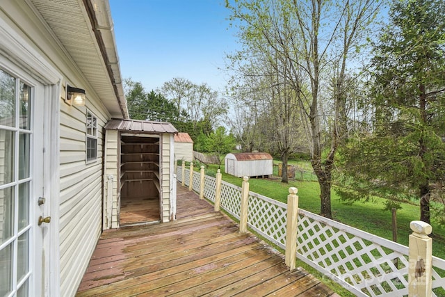 wooden deck with a yard, a storage shed, and an outbuilding
