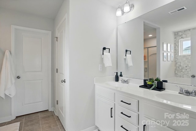 bathroom with tile patterned floors, a shower stall, a sink, baseboards, and visible vents