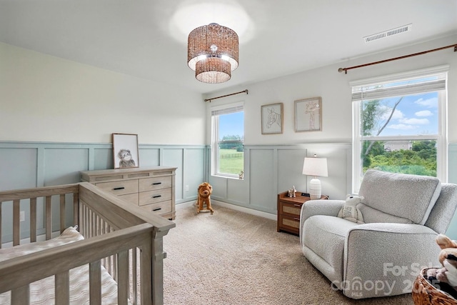 bedroom with a wainscoted wall, visible vents, a decorative wall, and carpet floors