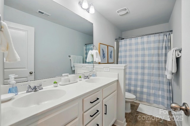bathroom featuring visible vents, toilet, and a sink
