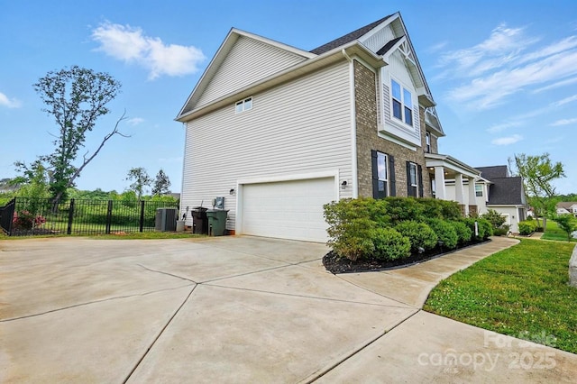 view of home's exterior with driveway, fence, central AC, and a garage