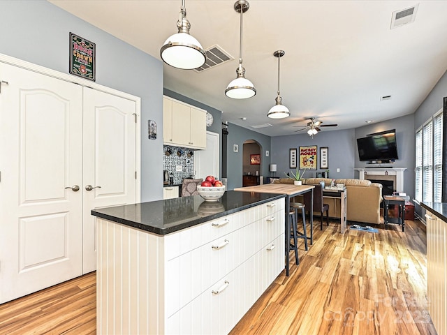 3914 Cassidy Dr, Waxhaw, NC 28173 - kitchen with ceiling fan, light wood-style floors, arched walkways, dark countertops, and decorative light fixtures