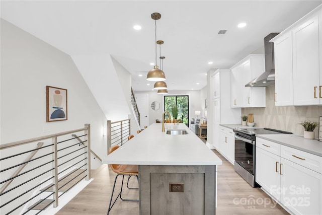 3449 Byrnes St, Charlotte, NC 28205 - kitchen featuring electric range, wall chimney exhaust hood, a sink, a center island with sink, and white cabinetry