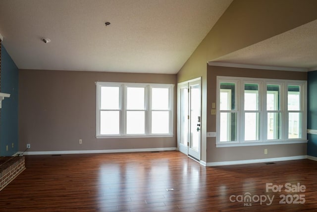 204 Foley Dr, Garner, NC 27529 - unfurnished living room featuring vaulted ceiling, wood finished floors, a textured ceiling, and baseboards