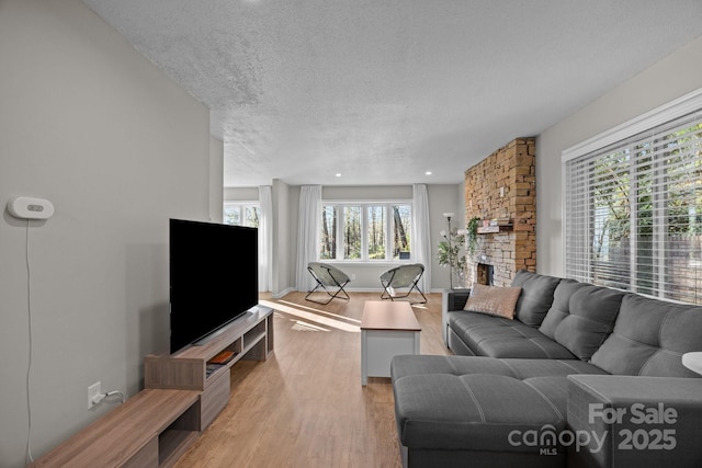 159 Long John Dr, Hendersonville, NC 28791 - living room featuring light wood-style floors, a stone fireplace, plenty of natural light, and a textured ceiling