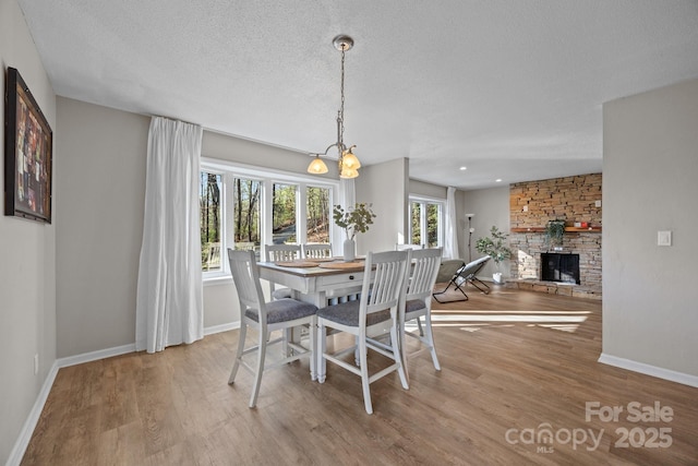 159 Long John Dr, Hendersonville, NC 28791 - dining room with a textured ceiling, a stone fireplace, a chandelier, wood finished floors, and baseboards
