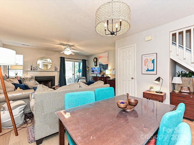 9305 Four Mile Creek Rd, Charlotte, NC 28277 - dining room featuring a fireplace, light wood-style floors, a textured ceiling, and ceiling fan with notable chandelier