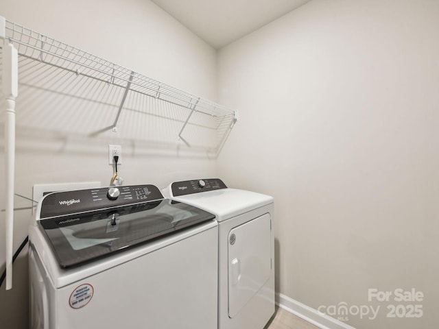 clothes washing area with washer and clothes dryer and baseboards