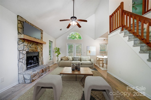 living area with a fireplace, stairway, a ceiling fan, and wood finished floors