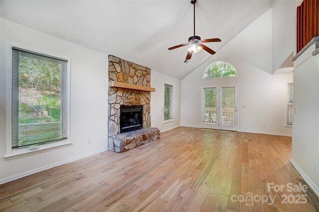 unfurnished living room with ceiling fan, light wood-type flooring, high vaulted ceiling, and a fireplace