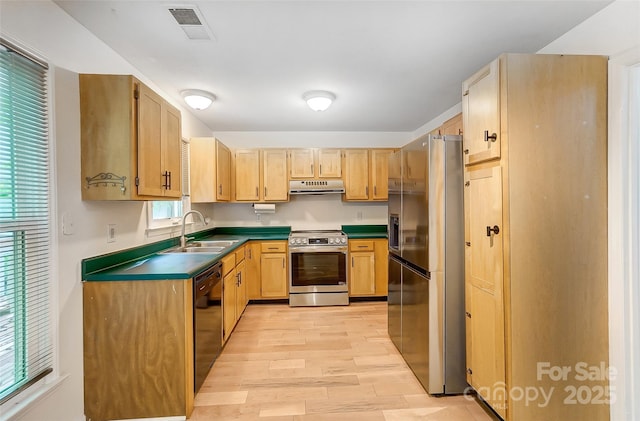 kitchen featuring dark countertops, under cabinet range hood, visible vents, stainless steel appliances, and a sink