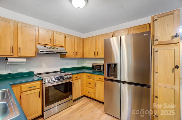 kitchen featuring under cabinet range hood, a sink, stainless steel appliances, light wood finished floors, and light brown cabinets
