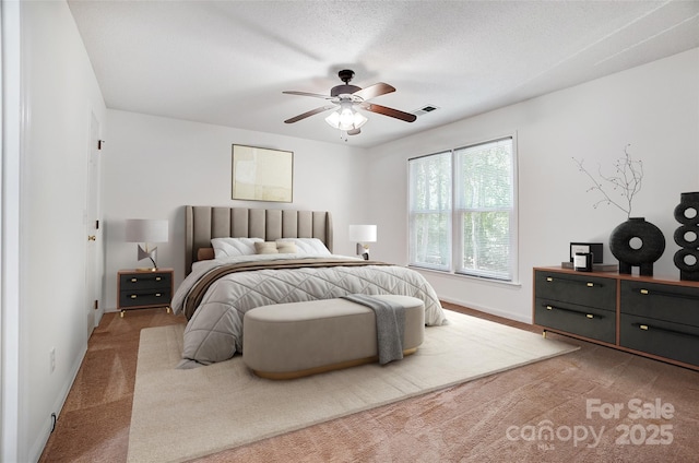 bedroom with baseboards, a textured ceiling, a ceiling fan, carpet floors, and visible vents