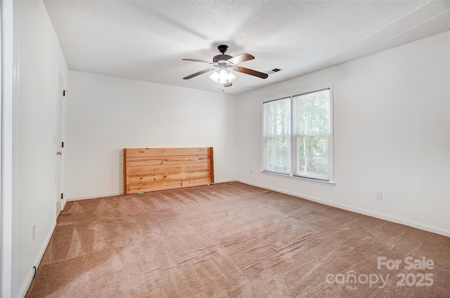 unfurnished room featuring visible vents, baseboards, ceiling fan, a textured ceiling, and carpet floors