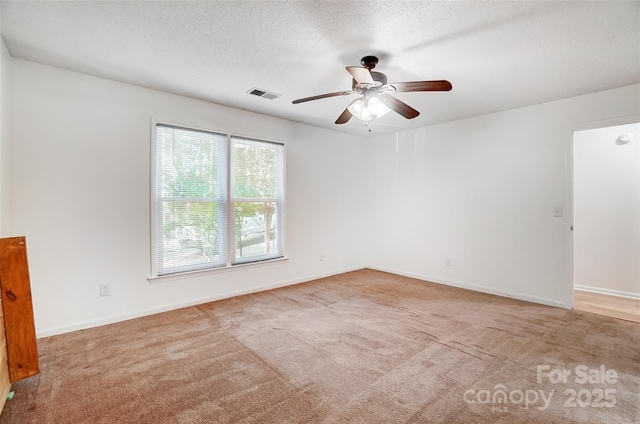 unfurnished room with visible vents, a textured ceiling, baseboards, and ceiling fan