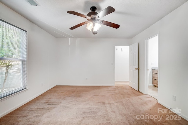 spare room with visible vents, ceiling fan, light colored carpet, and baseboards
