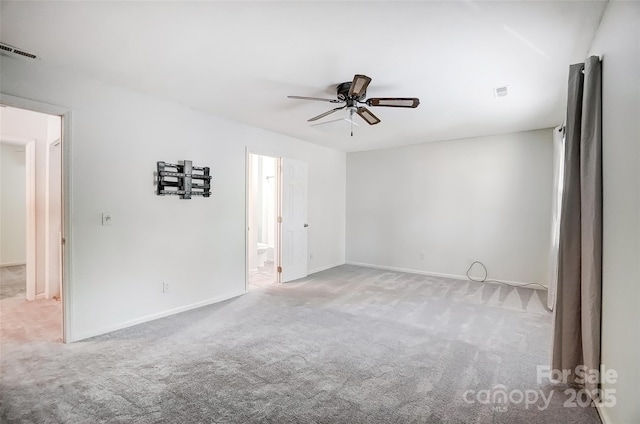 carpeted spare room with baseboards, a ceiling fan, and visible vents
