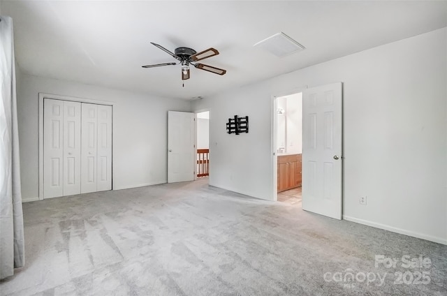 unfurnished bedroom featuring light carpet, a closet, baseboards, and connected bathroom