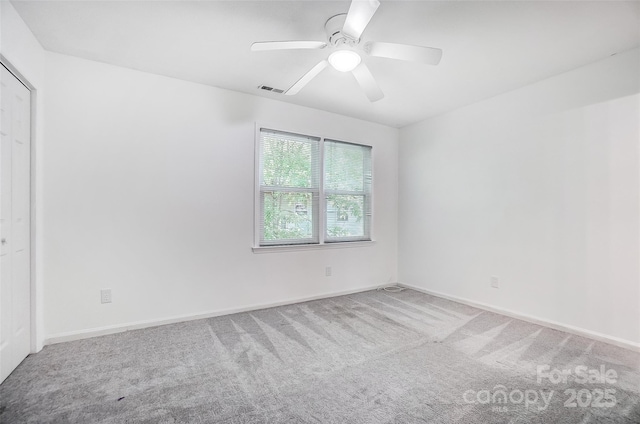 spare room featuring carpet floors, baseboards, a ceiling fan, and visible vents
