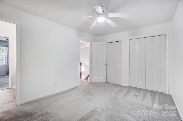 unfurnished bedroom with carpet floors, multiple closets, ceiling fan, and baseboards