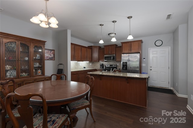 kitchen with stainless steel appliances, a center island with sink, visible vents, backsplash, and dark wood-style floors