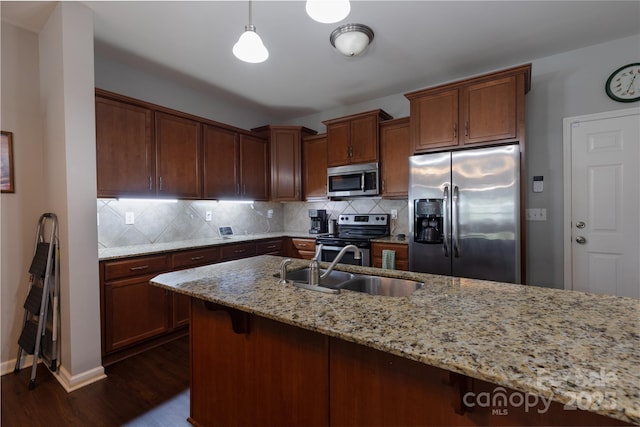 kitchen featuring a sink, stainless steel appliances, dark wood finished floors, backsplash, and light stone countertops