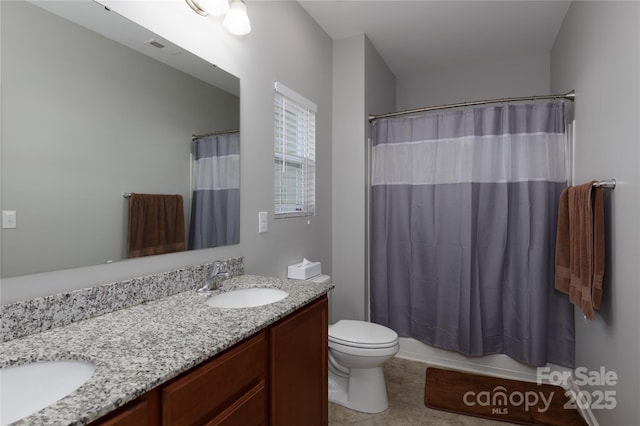 full bath featuring visible vents, a sink, double vanity, and toilet