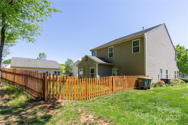 back of property featuring fence and a yard