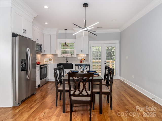 dining room with a chandelier, light wood-style flooring, recessed lighting, baseboards, and ornamental molding