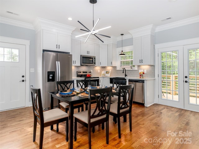 dining room with light wood-style floors, plenty of natural light, french doors, and visible vents
