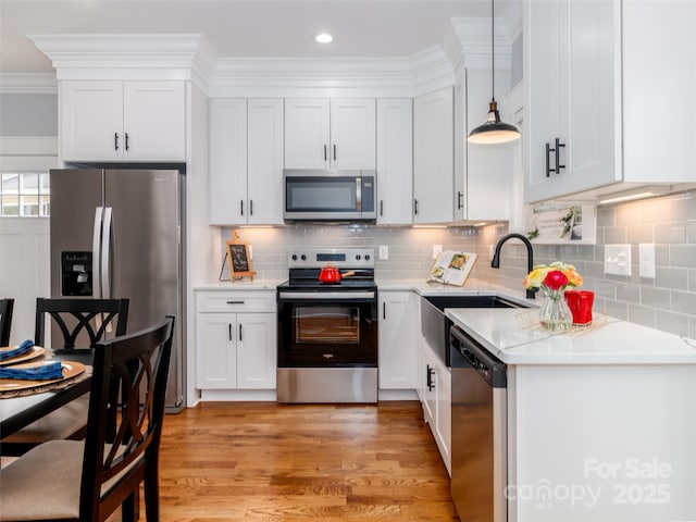 kitchen featuring a sink, appliances with stainless steel finishes, white cabinets, and light countertops