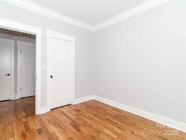 unfurnished bedroom featuring light wood finished floors, baseboards, visible vents, ornamental molding, and a closet