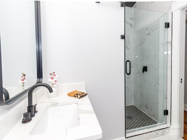full bathroom with a marble finish shower and a sink