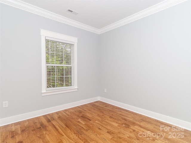 spare room featuring baseboards, visible vents, ornamental molding, and light wood-type flooring
