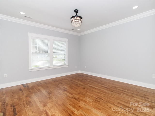 empty room featuring crown molding, baseboards, wood finished floors, and an inviting chandelier