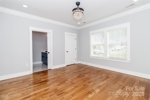 unfurnished bedroom featuring crown molding, an inviting chandelier, light wood-style floors, baseboards, and visible vents