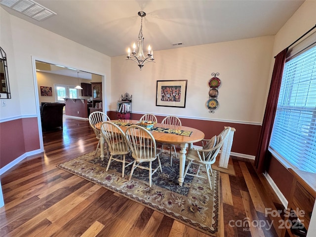 dining room with wood finished floors, visible vents, baseboards, and an inviting chandelier
