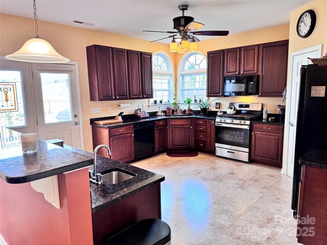 kitchen with dark countertops, visible vents, a sink, black appliances, and ceiling fan