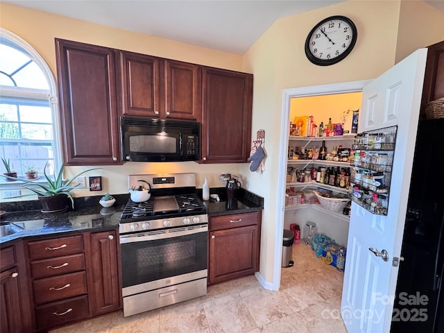 kitchen featuring gas range, black microwave, and dark stone counters