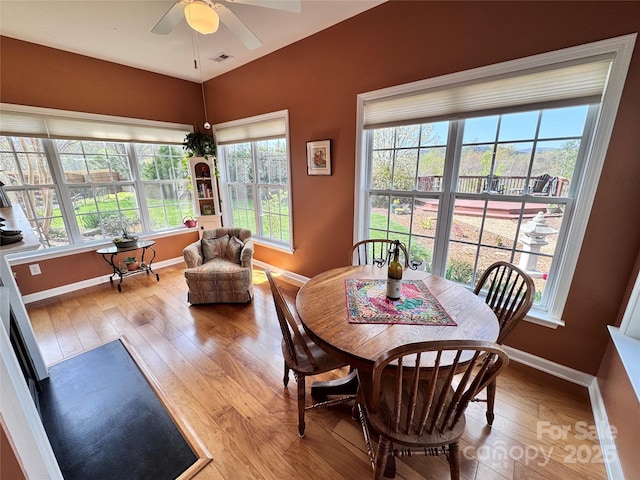 dining area featuring wood finished floors, visible vents, a ceiling fan, and baseboards