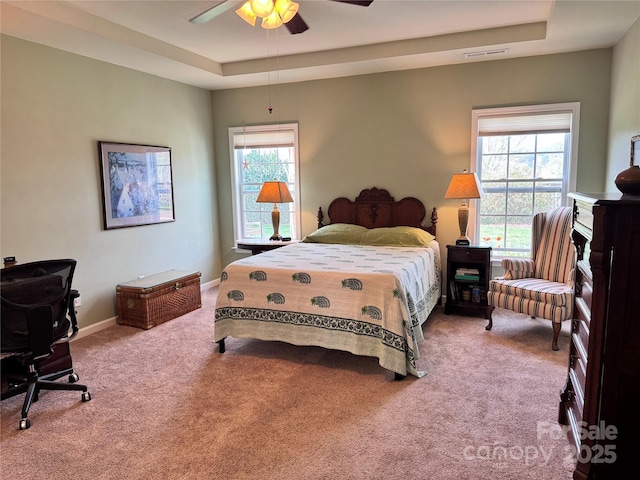 bedroom with carpet, a tray ceiling, visible vents, baseboards, and ceiling fan