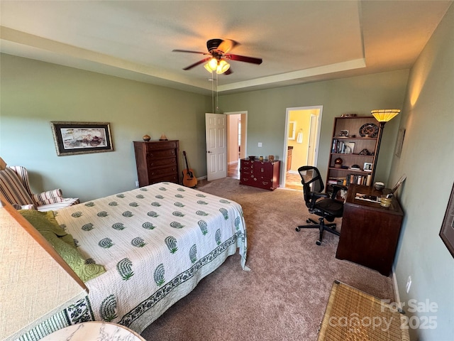 bedroom with ceiling fan, carpet flooring, and a tray ceiling