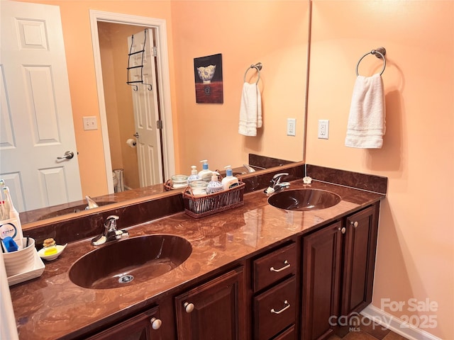 full bath with double vanity, baseboards, and a sink