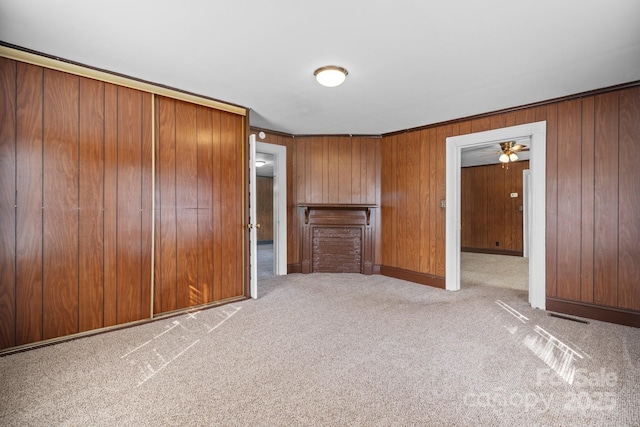 carpeted spare room featuring wooden walls and baseboards