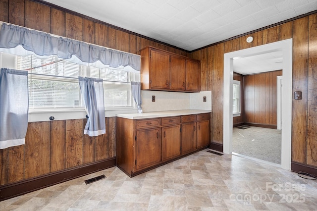 kitchen featuring a healthy amount of sunlight, wood walls, visible vents, and brown cabinets