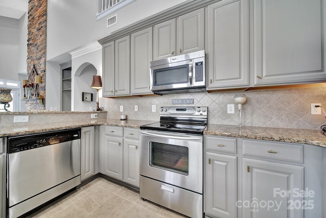 314 Wave Crest Dr, Tega Cay, SC 29708 - kitchen featuring a towering ceiling, stainless steel appliances, backsplash, light tile patterned flooring, and gray cabinetry
