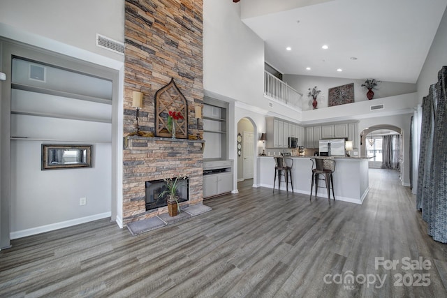 314 Wave Crest Dr, Tega Cay, SC 29708 - living room featuring high vaulted ceiling, wood finished floors, arched walkways, a fireplace, and visible vents