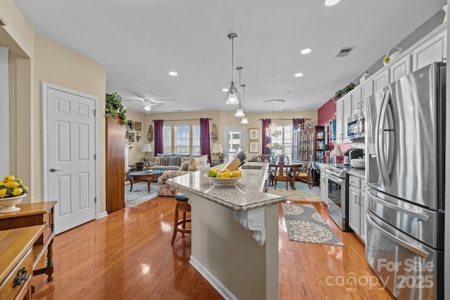 kitchen with recessed lighting, white cabinetry, a kitchen island, visible vents, and stainless steel appliances