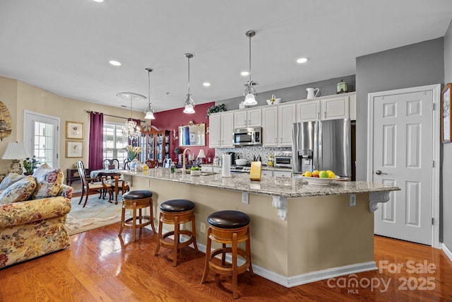 kitchen featuring white cabinets, light wood-type flooring, a breakfast bar area, and appliances with stainless steel finishes